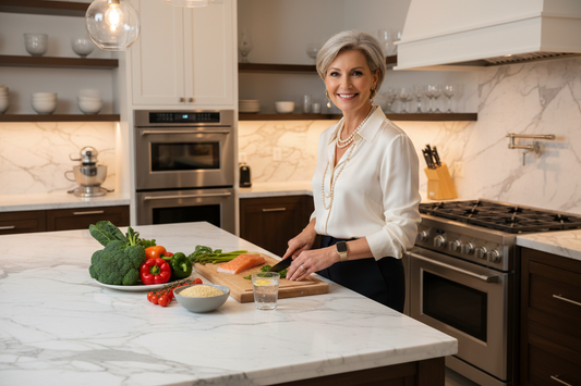Elegant woman in her 50s in a luxurious kitchen preparing a quick healthy evening meal with fresh vegetables and proteins on marble countertops